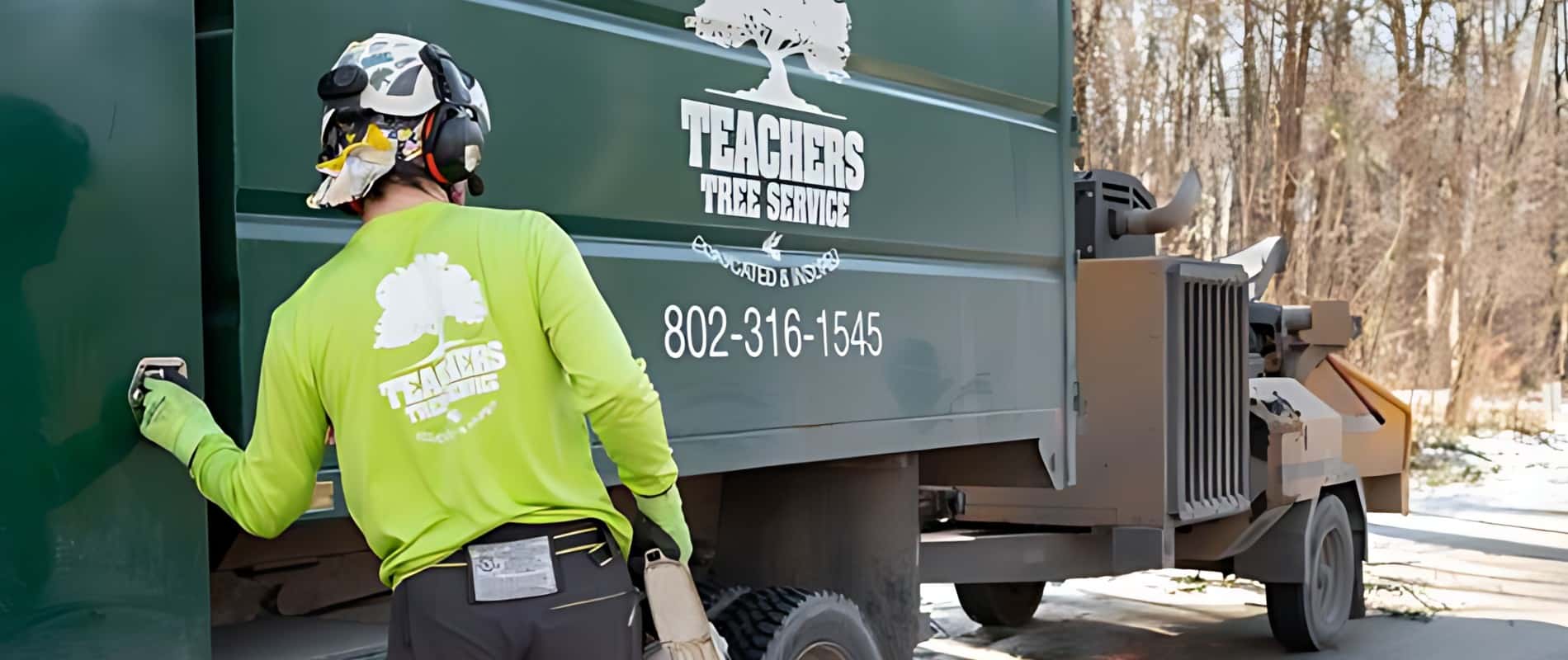 Teachers Tree Service crew member in branded gear next to a company truck and chipper