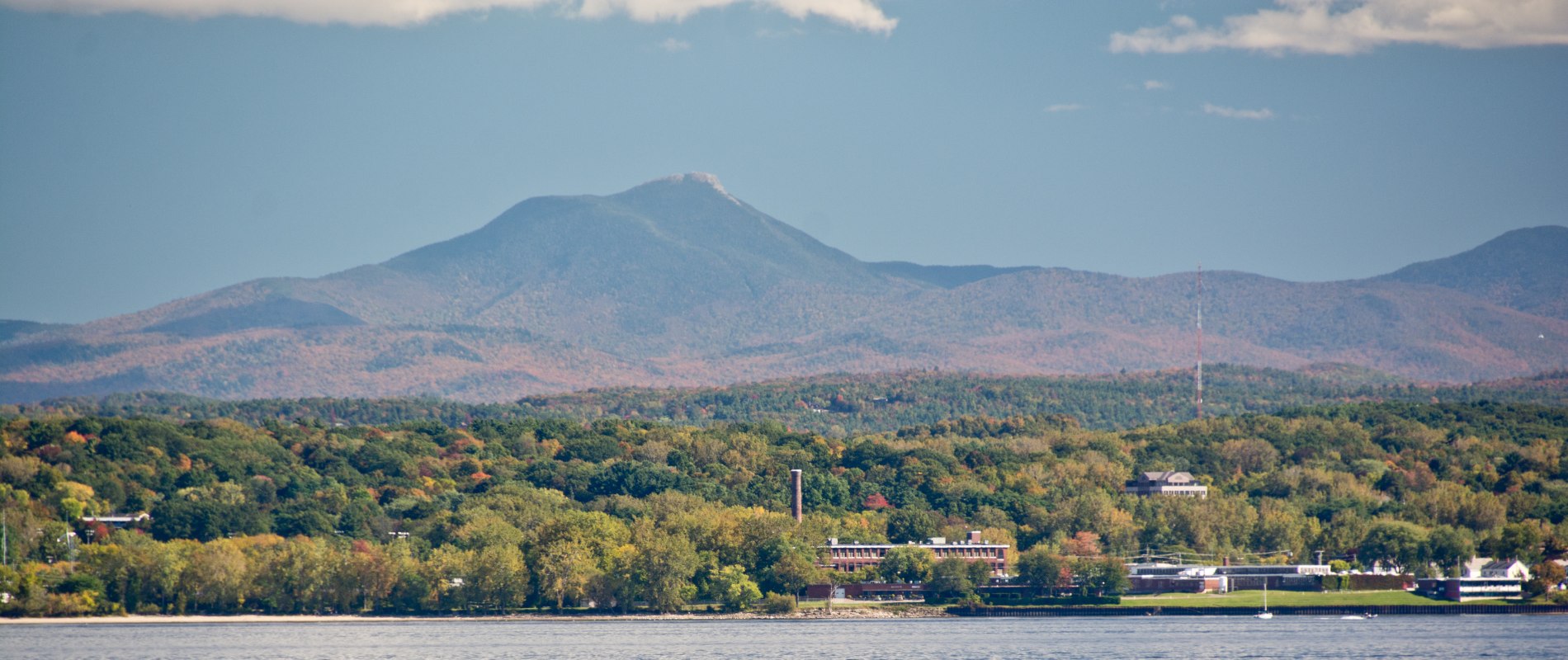 Scenic view of Lake Champlain shoreline with tree-covered hills and Green Mountains near Shelburne, VT