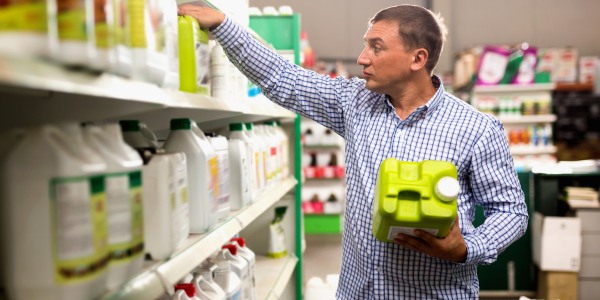 PHC technician selecting plant growth regulator products from a supply shelf