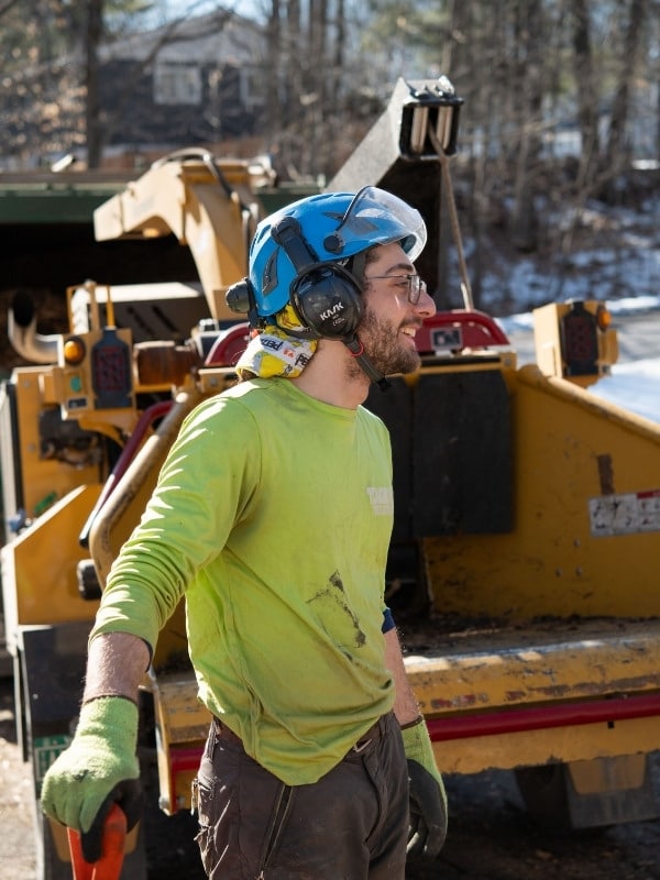 Teachers Tree Service ground crew member in safety gear with a chipper truck in the background