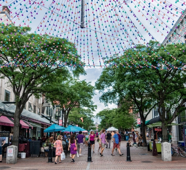 Shade trees lining Church Street Marketplace with pedestrians and string lights overhead in downtown Burlington