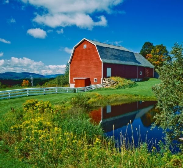 Classic red Vermont barn with trees and mountain views near Charlotte, VT