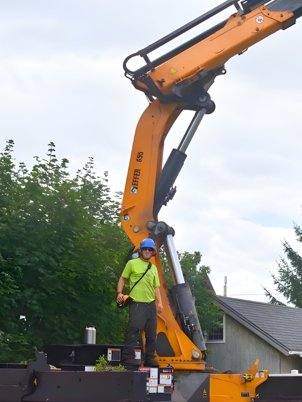 Teachers Tree Service crew member operating a knuckle boom crane during a tree removal job