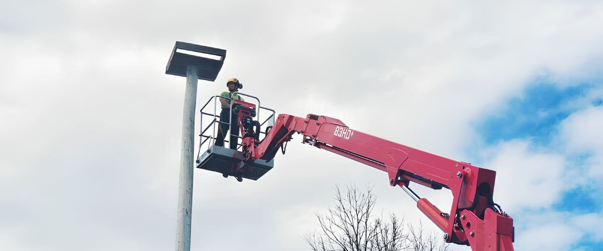 Guy fixing a platform on top of a pole that serves as a nest for a couple ospreys.